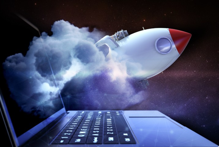a laptop with a rocket ship flying out that represents speed