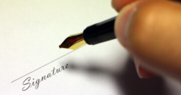a person writing a signature on a piece of paper