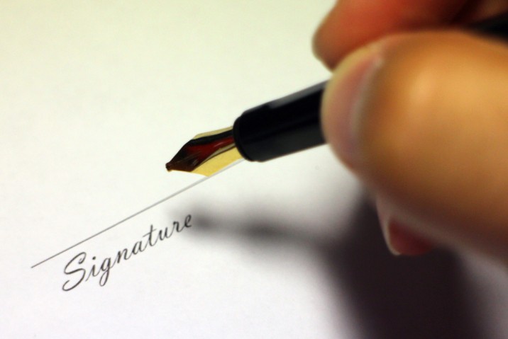a person writing a signature on a piece of paper