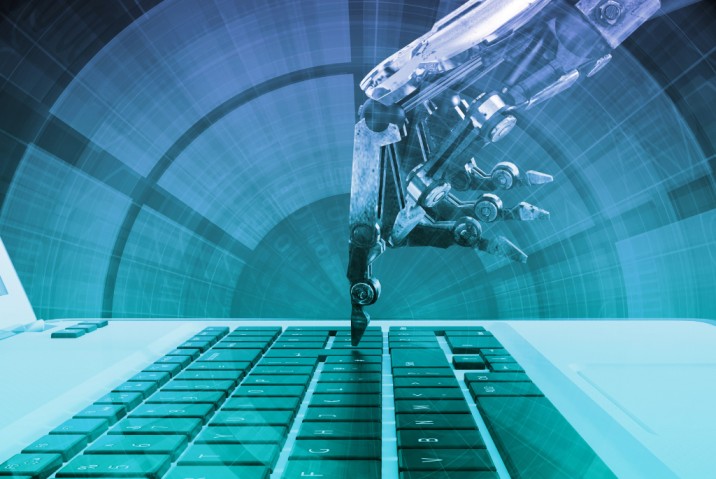 a robotic hand typing on a laptop keyboard representing automation