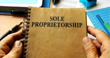 a person holding a notebook with the word sole proprietorship on it