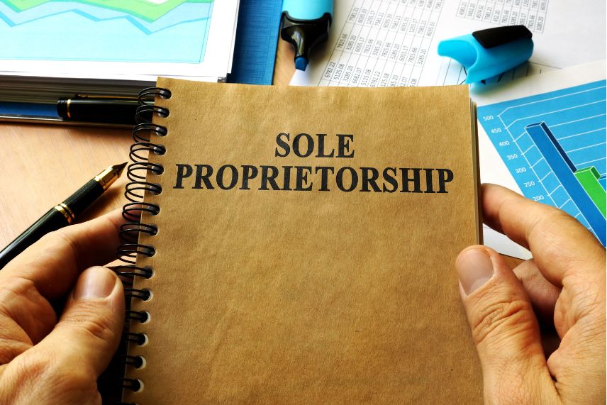 a person holding a notebook with the word sole proprietorship on it