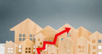 a red arrow going up in front of wooden houses representing tiered pricing